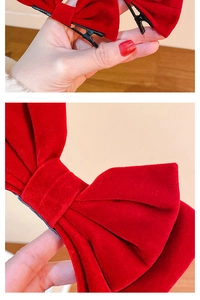 Détail d'un nœud en velours rouge montrant la texture du tissu et la pince crocodile noire