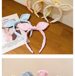Détail de la broderie florale sur des serre-têtes en tissu pastel avec oreilles de lapin