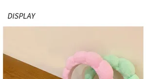 Detail von geflochtenen Haarbändern in Rosa und Mintgrün auf einem Holzschreibtisch