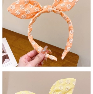 Détail de la broderie florale sur les bandeaux à oreilles de lapin orange et jaune