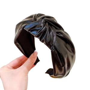 Shiny black PU leather knotted headband featuring a twist design for a stylish women's look