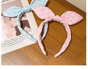 Détail de la broderie florale sur des serre-têtes à nœuds bleu clair et rose