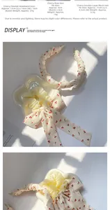 Détail de serre-tête et chouchous à motif cerise présentés sur un plateau fleuri