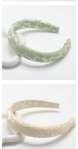 Detailed close-up of padded heart-patterned satin headbands in light green and cream