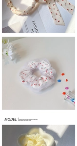 Détail de chouchou avec motif cerises et tulle blanc à pois et élastique en tissu jaune