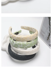 Detail view of four satin padded headbands with embossed heart patterns on a tray