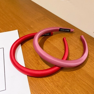 Elegant satin slim headbands in red and pink on a textured wooden background