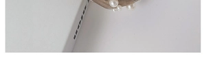 Detail eines grauen Chiffon-Haarreifs mit weißen Perlen auf einem weißen Buch