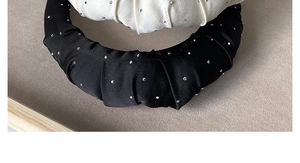 Detailed view of the pleated satin texture and shimmering rhinestones on the headband