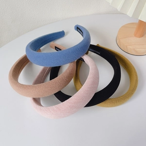 Five colorful waffle knit padded headbands in blue, pink, black and yellow on a white table