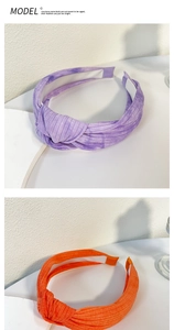 Dettaglio di due fasce per capelli tie-dye annodate in tessuto a coste viola e arancione
