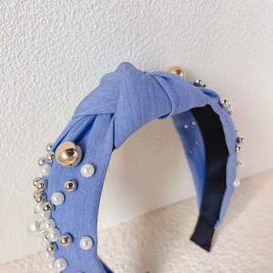 Light blue knotted headband with white pearls and metallic beads on textured fabric