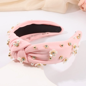Détail d'un serre-tête en tissu rose noué avec perles, strass et embellissements floraux