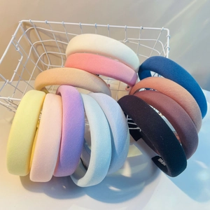 Detail showing various colors of handmade thick sponge headbands in a wire basket