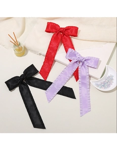 Detailed macro view showing the glossy satin texture and ruffled edges of large bow hair clips