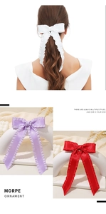Detailed view of elegant satin bow hair clips with ruffled edges and long ribbon tails