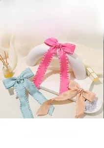 Detailed view of satin bow hair clips in pink, blue, and beige with ruffled edges