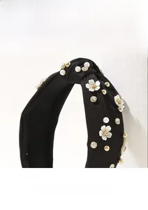 Dettaglio fascia nera annodata con fiori bianchi, perle e strass scintillanti
