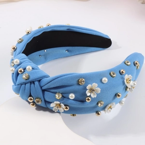 Détail du serre-tête noué bleu clair avec fleurs 3D blanches et perles nacrées