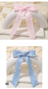 Detail of pink and light blue satin bow hair clips with delicate ruffled ribbon edges