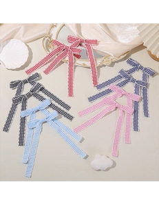 Detailed view of plaid bow hair clips with long ribbons and elegant scalloped edges