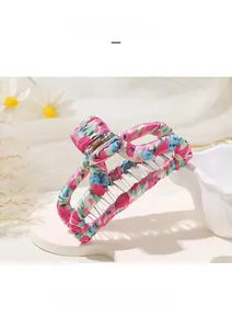 Détail d'une grande pince à cheveux en tissu fleuri rose et bleu sur dentelle blanche