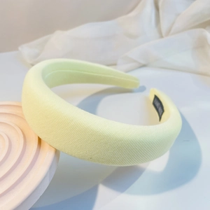 Detail of yellow padded sponge headband with handmade label on white textured cloth