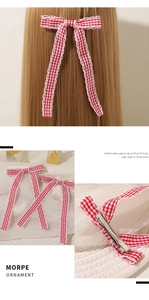 Detail of red gingham bow hair clip with white lace edges and metal duckbill fastener