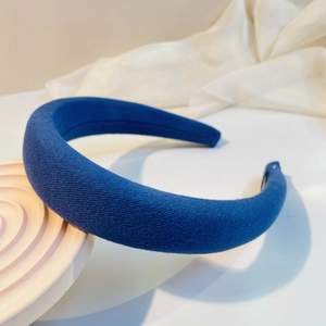 Close-up of Navy blue padded headband with diagonal twill fabric texture on white stand