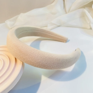 Detail of a padded beige sponge headband showing high-profile design and soft fabric texture