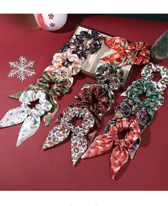 Vue détaillée des chouchous de Noël en satin avec motifs de nœuds festifs et aspect soyeux