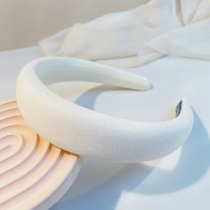 Detail of white padded sponge headband with soft knit texture on a pink tray