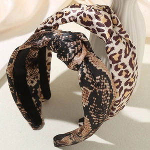 Fashionable leopard and snake print knotted headbands displayed on a modern ceramic vase