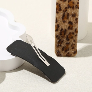 Leopard print faux fur BB hair clips with silver metal snap barrettes on beige background