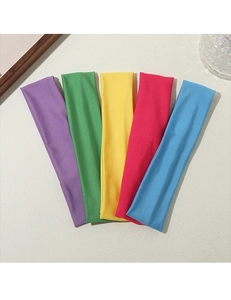 Close-up of five colorful elastic sports headbands in purple, green, yellow, pink, and blue