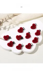 Detailed close-up of ten red velvet heart hair clips arranged on a white cloud display
