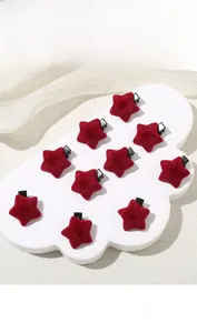 Close-up of red velvet star-shaped duckbill hair clips on white cloud display board