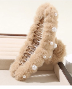 Dettaglio del fermaglio per capelli in peluche marrone chiaro con perle su vassoio beige