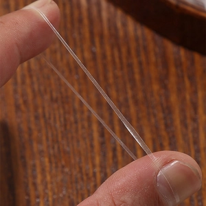 Durable high elasticity clear hair ties demonstrated with stretching action on wood