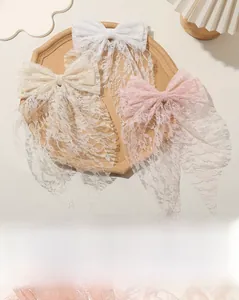 Detailed lace texture of bow hair clips in white, beige, and pink on a stone tray