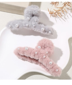 Dettaglio delle pinze per capelli in peluche grigio e rosa decorate con eleganti perle