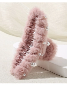 Dettaglio della molletta per capelli in peluche rosa con perle eleganti e denti interni
