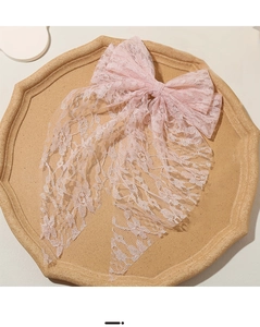 Detail of pink lace bow hair clip with floral patterns on a vintage wooden tray
