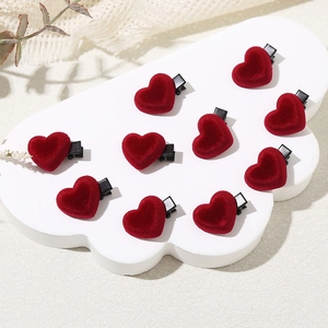 Set of 10 red velvet heart hair clips on a decorative white cloud display board