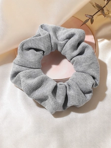Detail of grey knitted scrunchie on pink tray with elegant fabric background