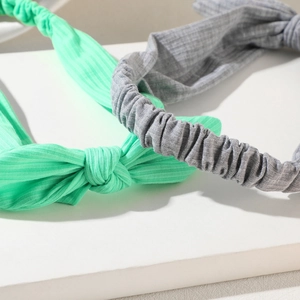 Close-up of mint green and grey bow headbands with soft textured elastic fabric