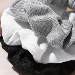 Three minimalist ribbed knit hair scrunchies in black, white, and grey for autumn styling