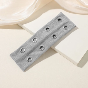 Detalle de diadema de punto gris con ocho ojales metálicos estilo punk en soporte blanco
