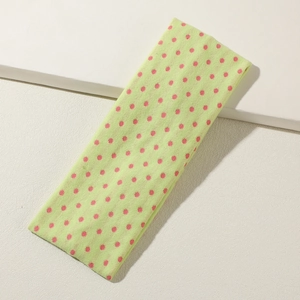 Detail eines limettengrünen Yoga-Stirnbands mit rosa Punkten auf weißem Hintergrund