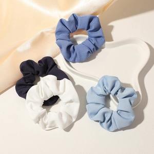 Close-up of four ribbed blue and white scrunchies in a decorative heart tray